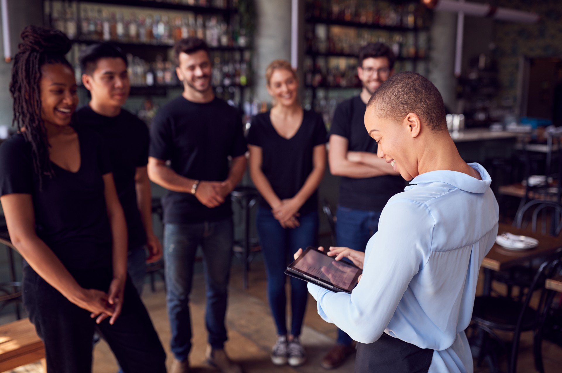 Female Restaurant Manager With Digital Tablet Giving Team Talk To Waiting Staff